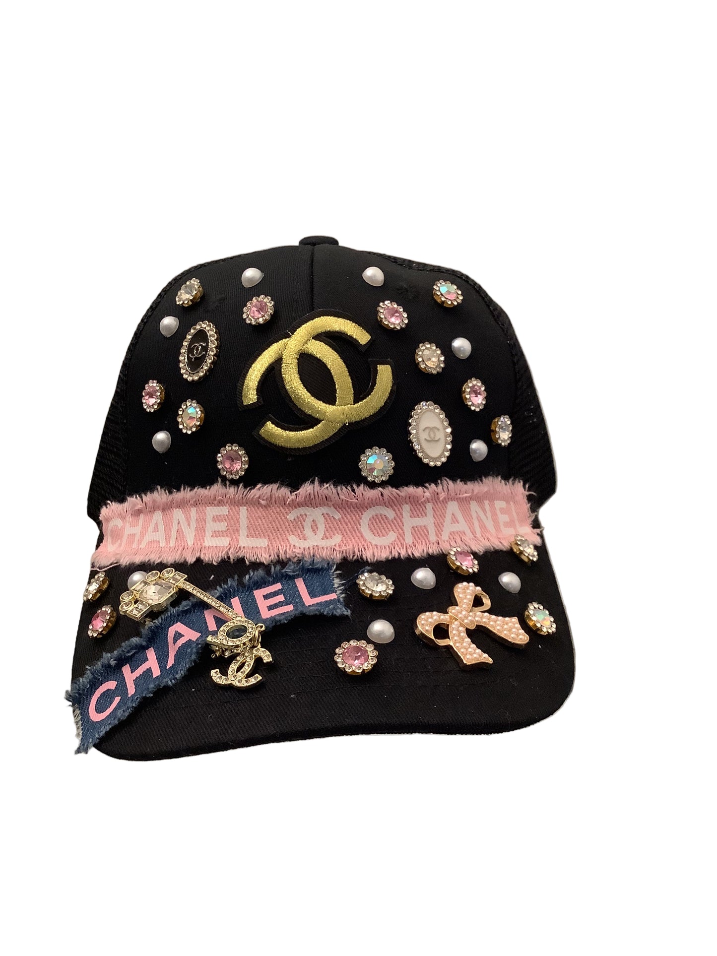Black embellished handbag with Chanel logo and pink headband on a white surface.